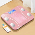 Pink digital body fat scale on a wooden surface with a smartphone displaying app.