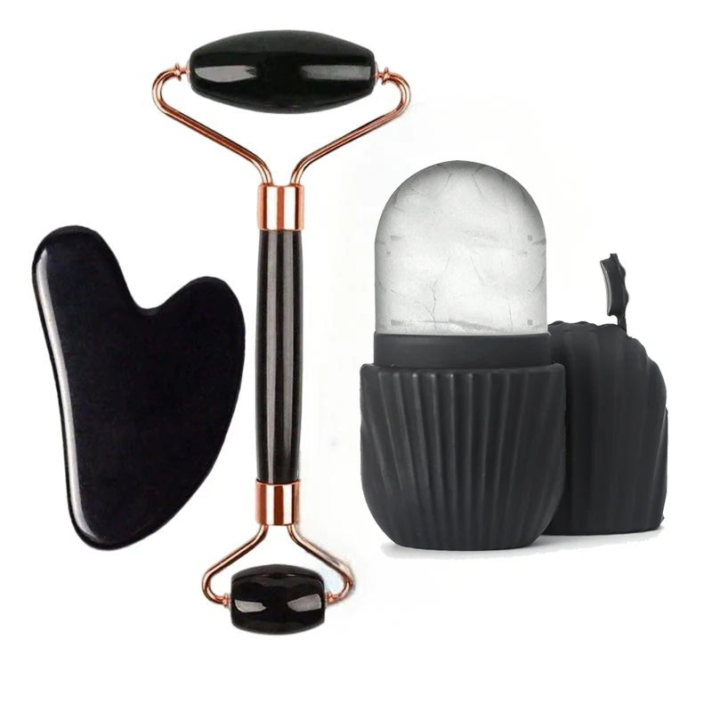 Black and rose gold facial massage set including a double-ended roller tool, a gua sha blade, and a black silicone storage case with a clear dome container, shown on a white background.